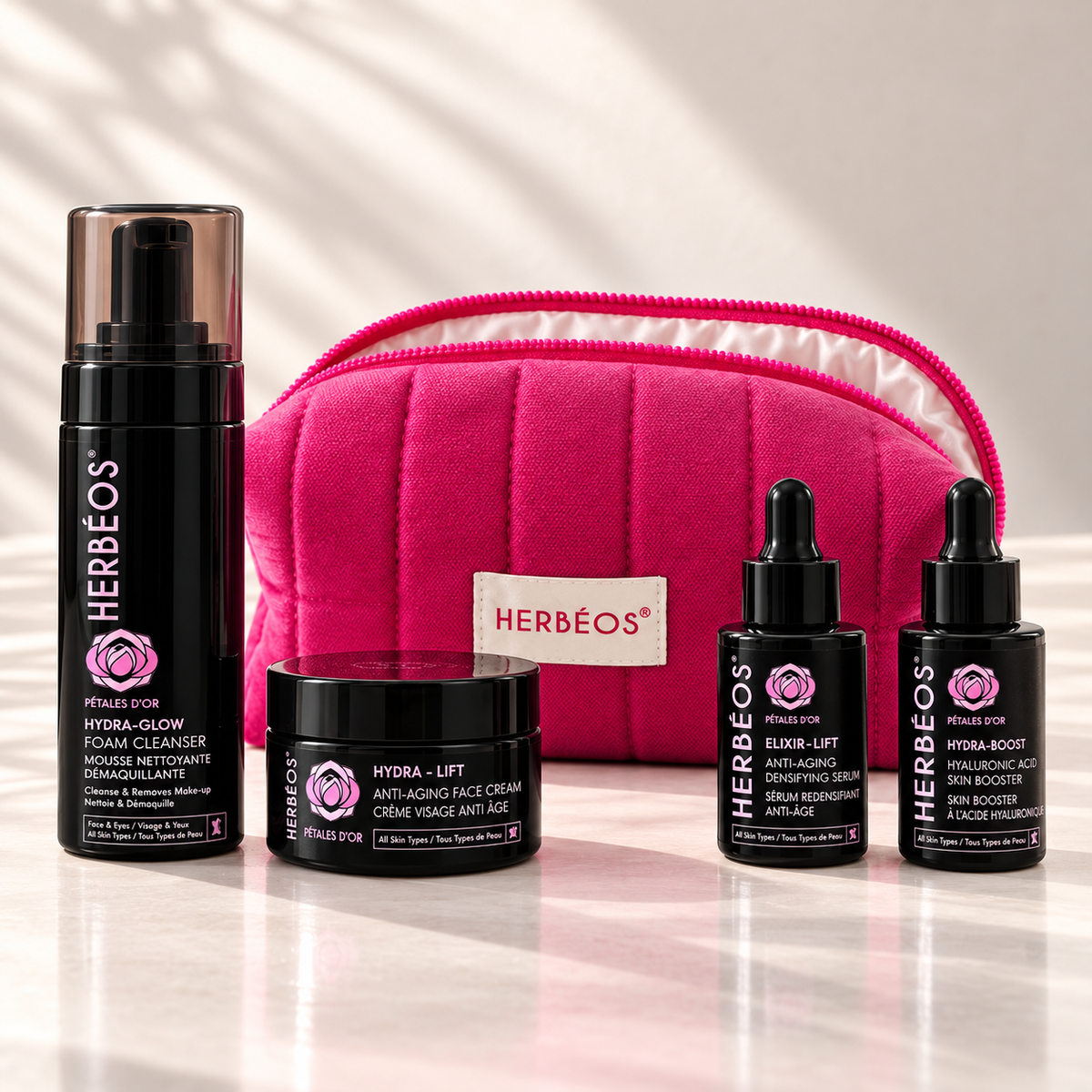 Kit Essentiels Pétales d'Or Herbéos : mousse Hydra Glow, crème Hydra Lift, sérum Elixir Lift, booster Hydra-Boost et trousse matelassée rose