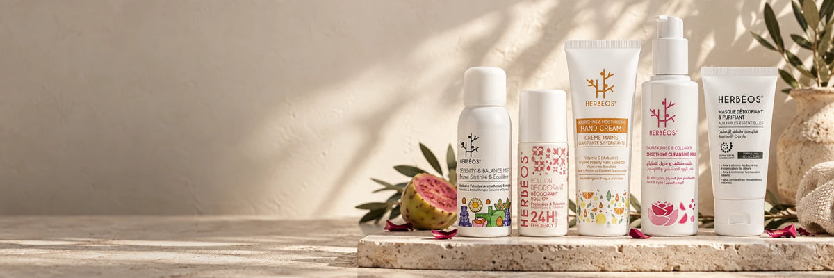 Soins naturels Herbéos sur une tablette en travertin : brume, déodorant roll-on, crème mains, lait démaquillant et masque détoxifiant, avec figue de barbarie et pétales de rose